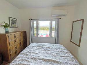 a bedroom with a bed and a dresser and a window at Palmeras Beach Apartments - Playa Santa in Guanica