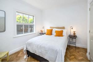 a bedroom with a bed with orange pillows and a window at Karoo House in Greytown