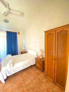 1 dormitorio con cama blanca y cortinas azules en Hotel Boutique Eden Costa en Santa Cruz - Huatulco