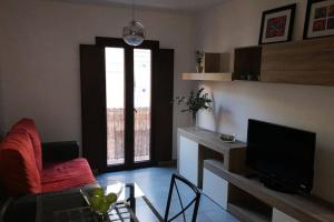 ein Wohnzimmer mit einem roten Stuhl und einem TV in der Unterkunft Fabuloso apartamento en Triana in Sevilla