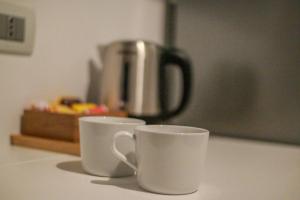 two white cups sitting on a counter with a coffee pot at La Dimora di Nonna Maria in Maiori