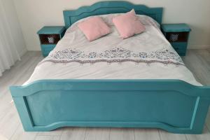 a blue bed with two pink pillows on it at Pristina Apartments in Prishtinë