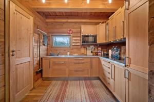 a large kitchen with wooden cabinets and a rug at Srub Pod Lípou - Skryje 