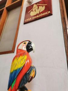 una estatua de un loro colorido sentada junto a una pared en Hospedaje Casa Amazónica Iquitos, en Iquitos