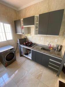 uma cozinha com um lavatório e uma máquina de lavar roupa em Apartamento Bela vista II em Guaratinguetá