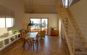 a kitchen and dining room with a wooden table and a staircase at Gamsfels Josephine Galeriewohnung in Langen bei Bregenz