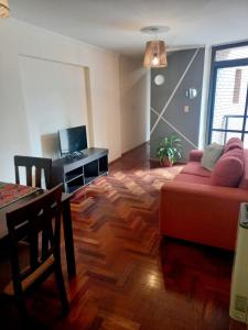 uma sala de estar com um sofá vermelho e uma mesa em Dpto dos dormitorios en Nueva Córdoba em Córdoba