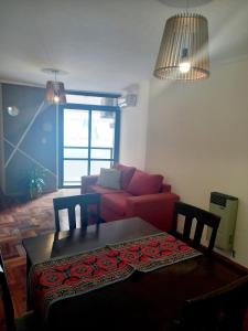 a living room with a table and a red couch at Dpto dos dormitorios en Nueva Córdoba in Cordoba