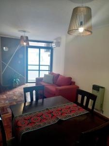 sala de estar con mesa y sofá rojo en Dpto dos dormitorios en Nueva Córdoba en Córdoba