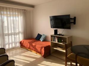 1 dormitorio con 1 cama y TV de pantalla plana en Hermoso Depto frente al mar Brown 782 en Mar del Plata