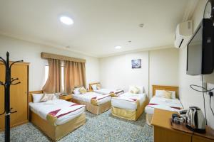 a hotel room with three beds and a tv at فندق الفنار العزيزية in Makkah