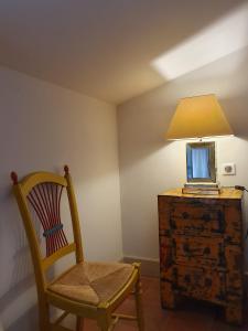 a room with a chair and a lamp on a dresser at La petite hostellerie in Uzès