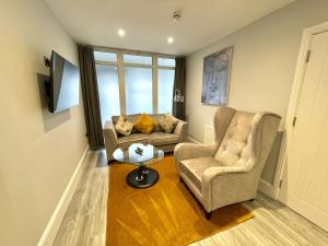 ein Wohnzimmer mit 2 Stühlen, einem Sofa und einem Tisch in der Unterkunft LYMM LIVING in Warrington