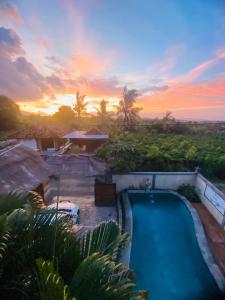 a swimming pool with a sunset in the background at Menjangan Sari in Banyuwedang