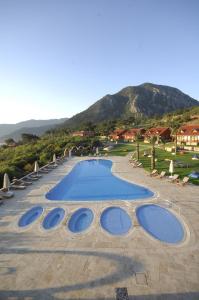 a large swimming pool in a resort with a mountain at Club Sun Village Hotel in Adrasan