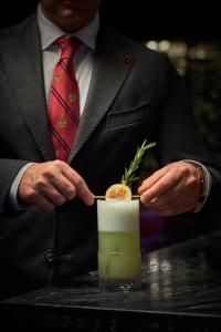 un hombre con traje y corbata sosteniendo una bebida en The St. Regis Washington, D.C., en Washington