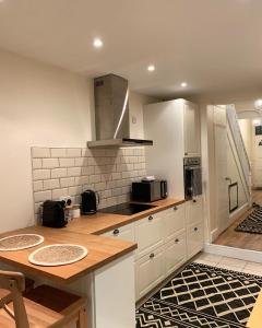 Una cocina con gabinetes blancos y una encimera de madera. en Cardiff Home, en Cardiff