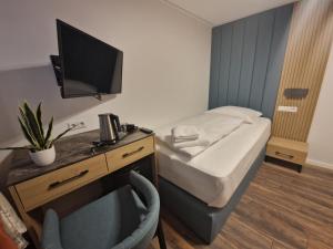 a small room with a bed and a desk with a television at Hotel Lottstetten in Lottstetten