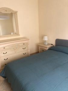 een slaapkamer met een bed en een dressoir met een spiegel bij Casa di Rosa in San Leone