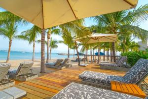 a wooden deck with chairs and umbrellas on a beach at Vallarta Gardens V4 -Alberca y Roof Garden Private in Cruz de Huanacaxtle