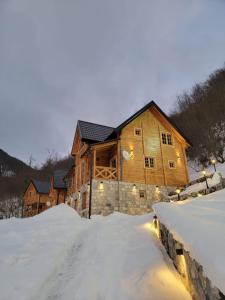 a log cabin in the snow with lights on it at Planinska kuca Grujic in Kolašin