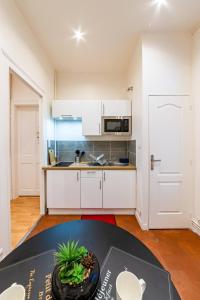 a kitchen with white cabinets and a table at Suite Amazonia ~ Balnéo ~ Arrivée Autonome in Rouen