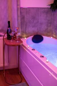 a purple bathroom with a tub with two glasses of wine at Suite Amazonia ~ Balnéo ~ Arrivée Autonome in Rouen