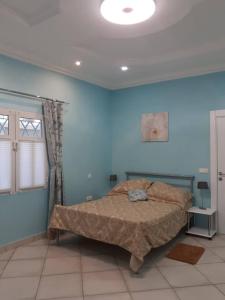 1 dormitorio con 1 cama en una pared azul en Babhilds Residence, en Bakau