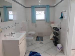 bagno bianco con lavandino e servizi igienici di Babhilds Residence a Bakau
