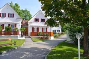 バート・ヴァルタースドルフにあるApartment in Bad Waltersdorf - Steiermark 43929の赤い窓とベンチのある白い家