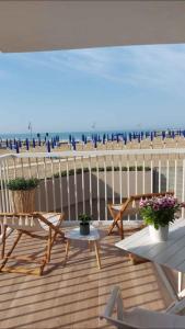 a deck with chairs and tables and a beach at Apartment in Porto Santa Margherita 43993 in Porto Santa Margherita di Caorle
