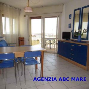 a living room with a dining room table and blue chairs at Apartment in Porto Santa Margherita 43993 in Porto Santa Margherita di Caorle