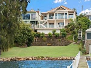 a large house on the shore of a body of water at Central Coast Moon Lake Resort in Sydney