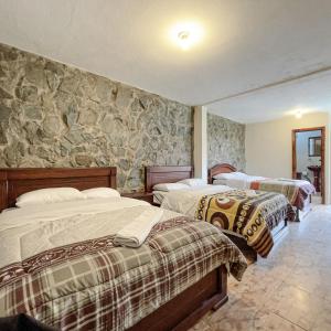 a bedroom with two beds and a stone wall at Quinta San Martín in Cuenca