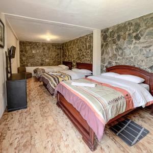 two beds in a room with stone walls at Quinta San Martín in Cuenca