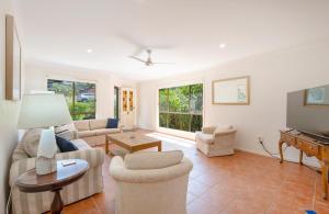 a living room with a couch and chairs and a tv at Four Beaches-LJHooker Yamba in Yamba