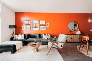 a living room with a black couch and an orange wall at Gallery Retreat - Skyline Views - Zuni Lofts in Denver