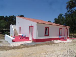 a small white house with chairs and a table at Herdade Rodrigo Afonso in São Teotónio