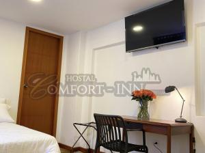 HOSTAL COMFORT- INN by BRILLIANT في كيتو: غرفة نوم مع مكتب مع تلفزيون على الحائط