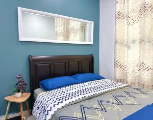 1 dormitorio con 1 cama con paredes azules y espejo en Bandar Melaka Family Bungalow Private Pool BBQ WiFi Netflix, en Melaka