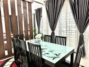 ein Esszimmer mit einem Tisch und Stühlen mit Vorhängen in der Unterkunft Bandar Melaka Family Bungalow Private Pool BBQ WiFi Netflix in Malakka