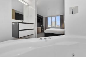 Allurity Hotel في هوبارت: حمام ابيض مع سرير ومرآة
