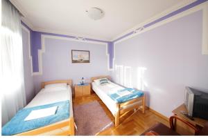 Habitación pequeña con 2 camas y TV. en Guest House Pansion 10, en Cetinje