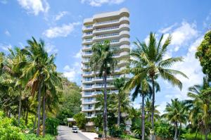 a tall building with palm trees in front of a road at Allure on Hamilton Island by HIHA in Hamilton Island