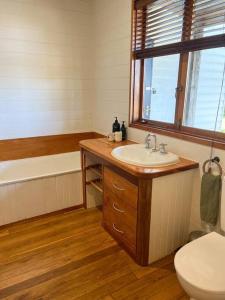 a bathroom with a sink and a toilet and a window at Pt Hesse Luxury Coastal Homestead in Port Campbell