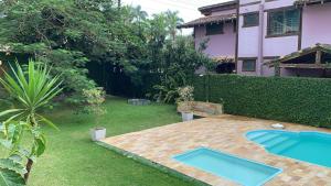 a backyard with two swimming pools in the grass at Linda Casa em Camburizinho 100 m da praia in São Sebastião