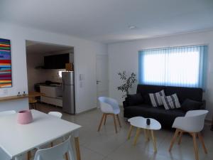 a living room with a black couch and white chairs at Dpto Turístico Renato Mendoza in Mendoza