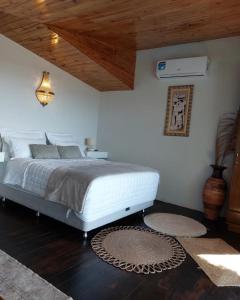 1 dormitorio con cama blanca y techo de madera en Vista Lago Suites PY en Itauguá