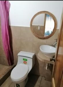 y baño con aseo, lavabo y espejo. en Casa Bony, en Montañita