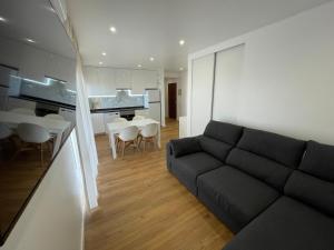 sala de estar con sofá negro y cocina en Monte Gordo South Pearl Apartment, en Monte Gordo